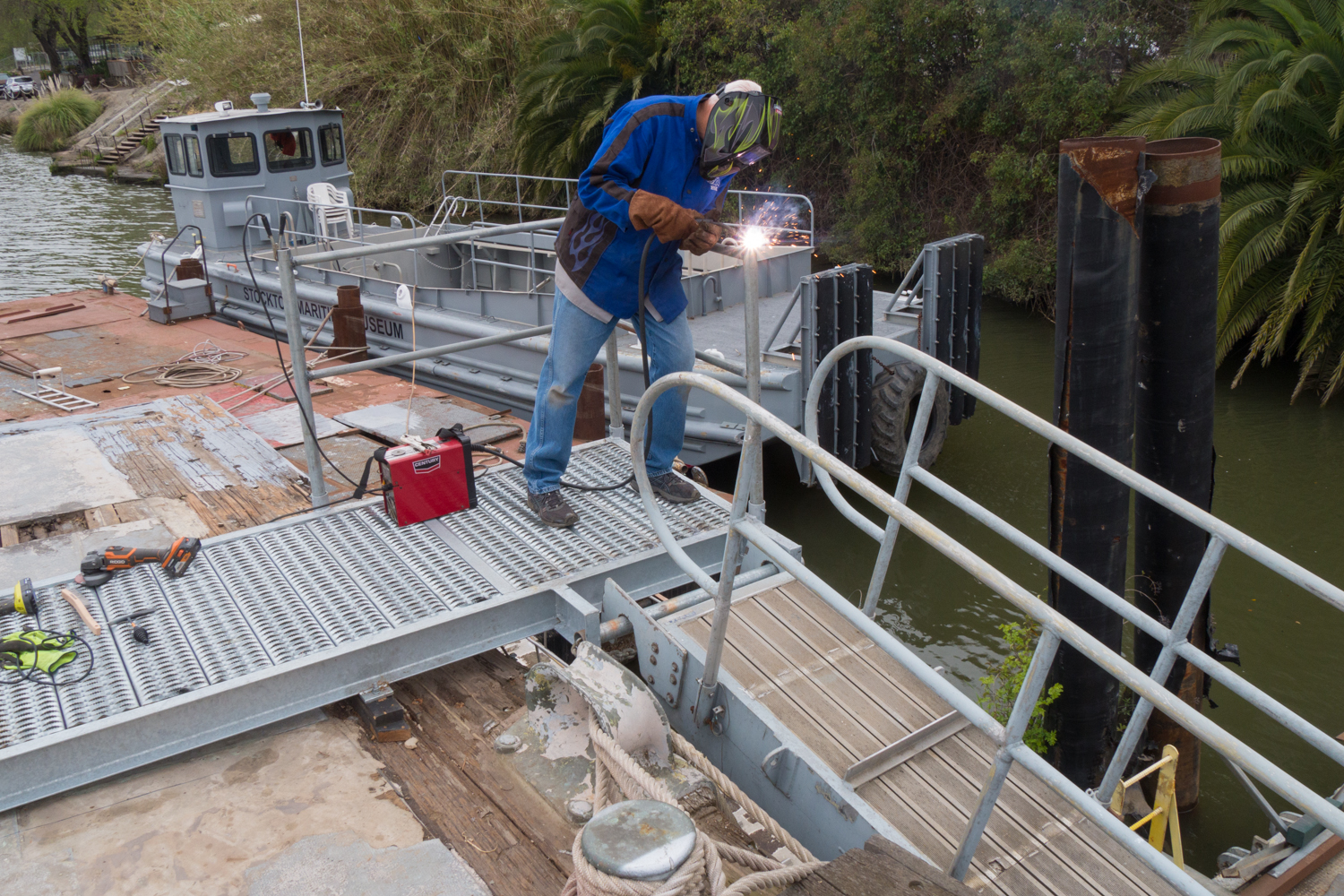 Volunteer welding metal railings on the USS Lucid as part of ongoing restoration efforts.