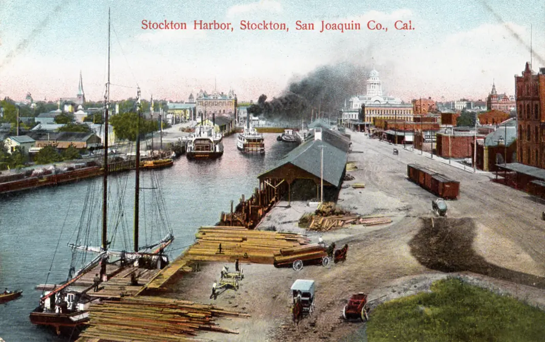 Historic postcard view of Stockton Harbor showing ships, docks, warehouses, and the downtown waterfront during the early 1900s, illustrating Stockton's role as California's inland port and maritime shipping center.