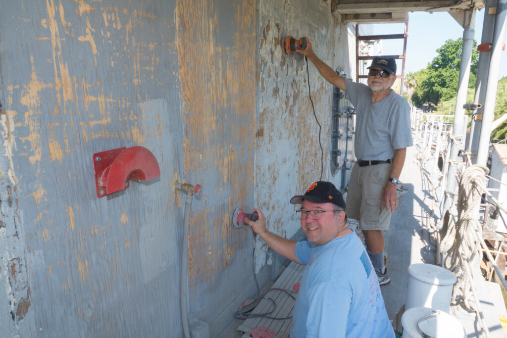 Volunteer sanding and restoring the ship's wooden hull.