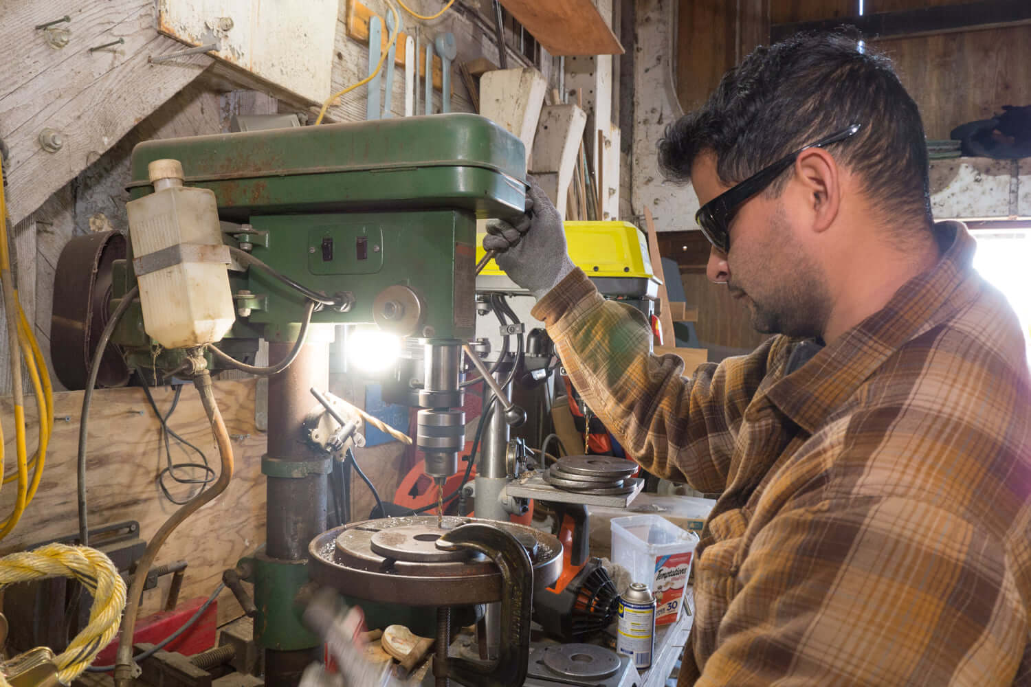 Volunteer operating a drill press while fabricating replacement parts for the USS Lucid restoration.