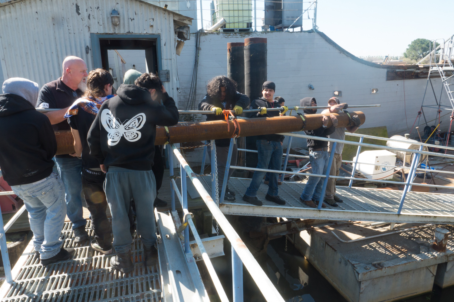 Volunteers working together to move heavy materials during a restoration workday aboard the USS Lucid.