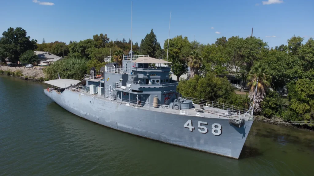 Aerial view of the USS Lucid (MSO-458) in 2025 after 14 years of volunteer restoration, highlighting the ship's restored exterior and ongoing preservation efforts.
