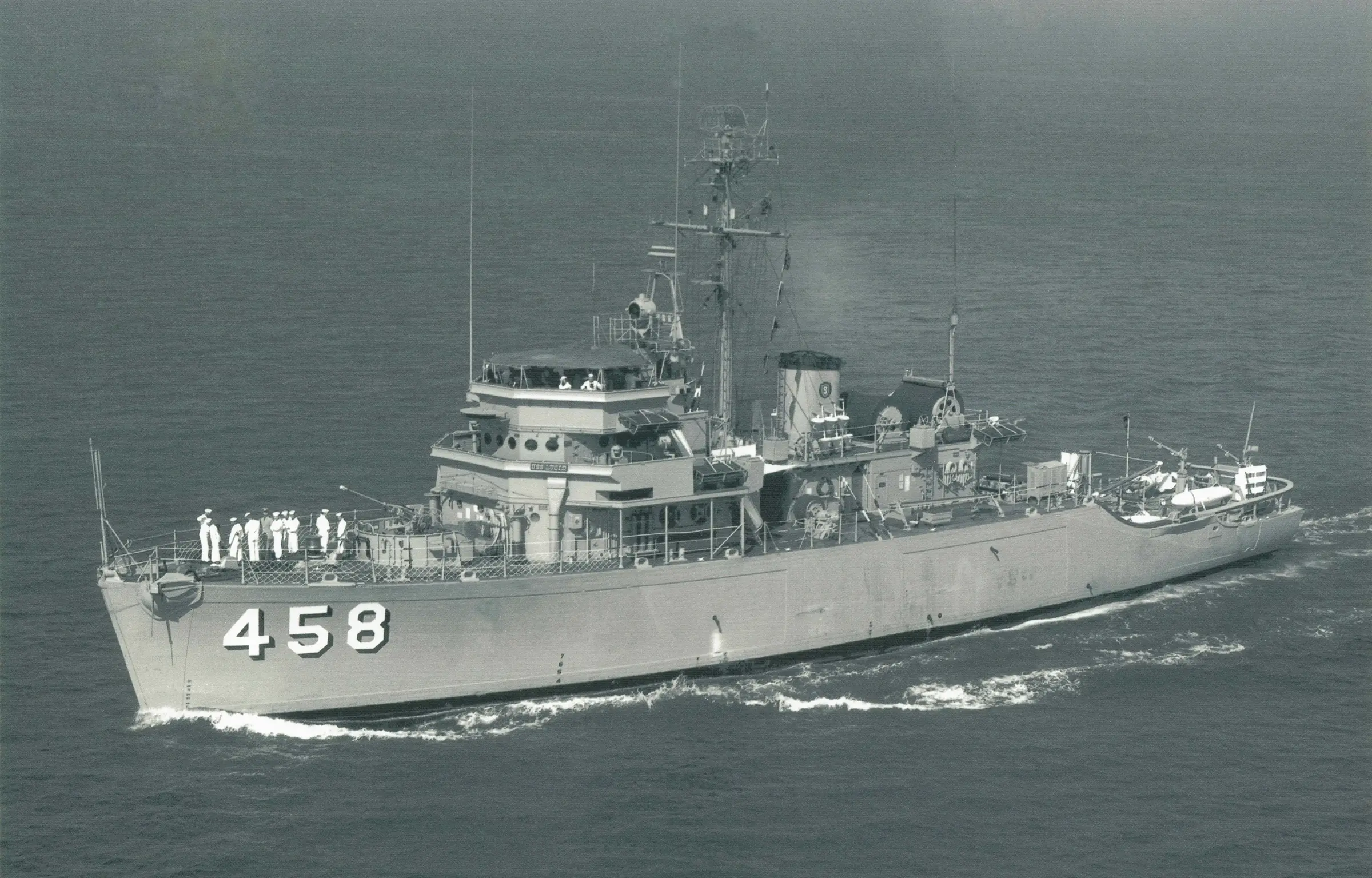 Historic photograph of the USS Lucid (MSO-458) underway at sea during her active U.S. Navy service, showing the Aggressive-class oceangoing minesweeper with her crew on deck.