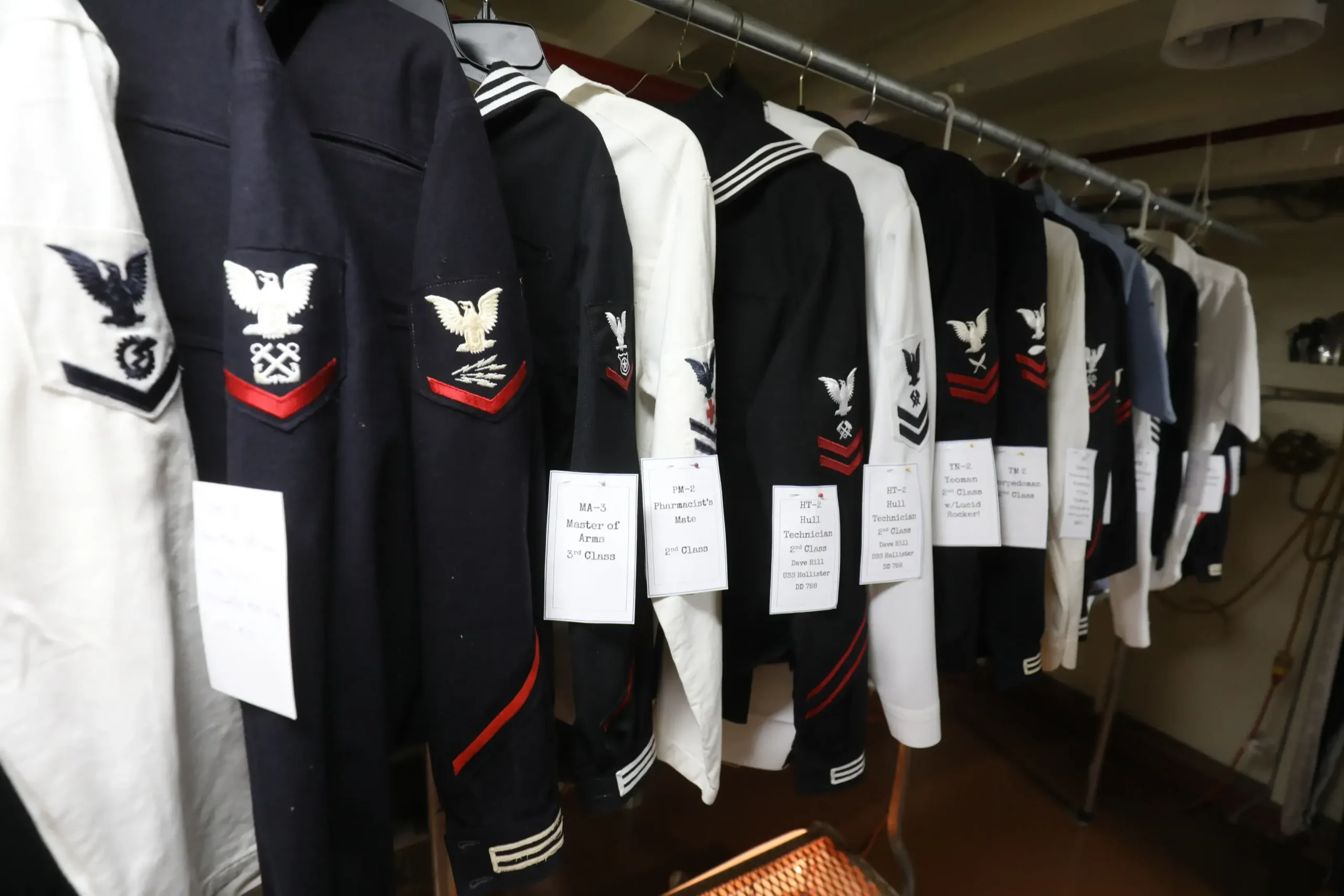 Collection of U.S. Navy uniforms displayed aboard the USS Lucid, representing the type of historical artifacts and memorabilia preserved through donations to the Stockton Maritime Museum.