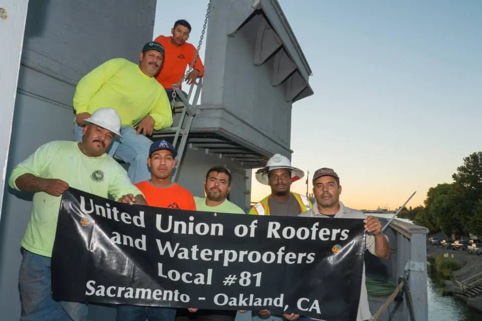 Volunteers from United Union of Roofers together on the deck of the USS Lucid during a restoration workday.
