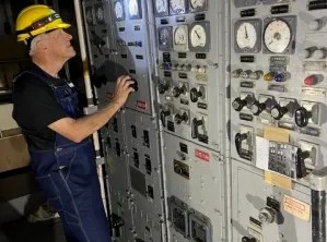 Volunteer inspecting and restoring electrical equipment aboard the USS Lucid.