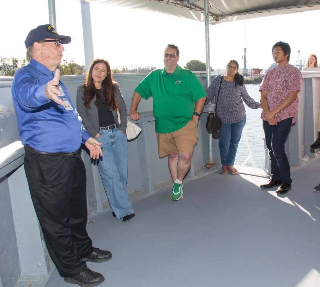 Visitors listen to a volunteer guide during an open house tour aboard the USS Lucid minesweeper.