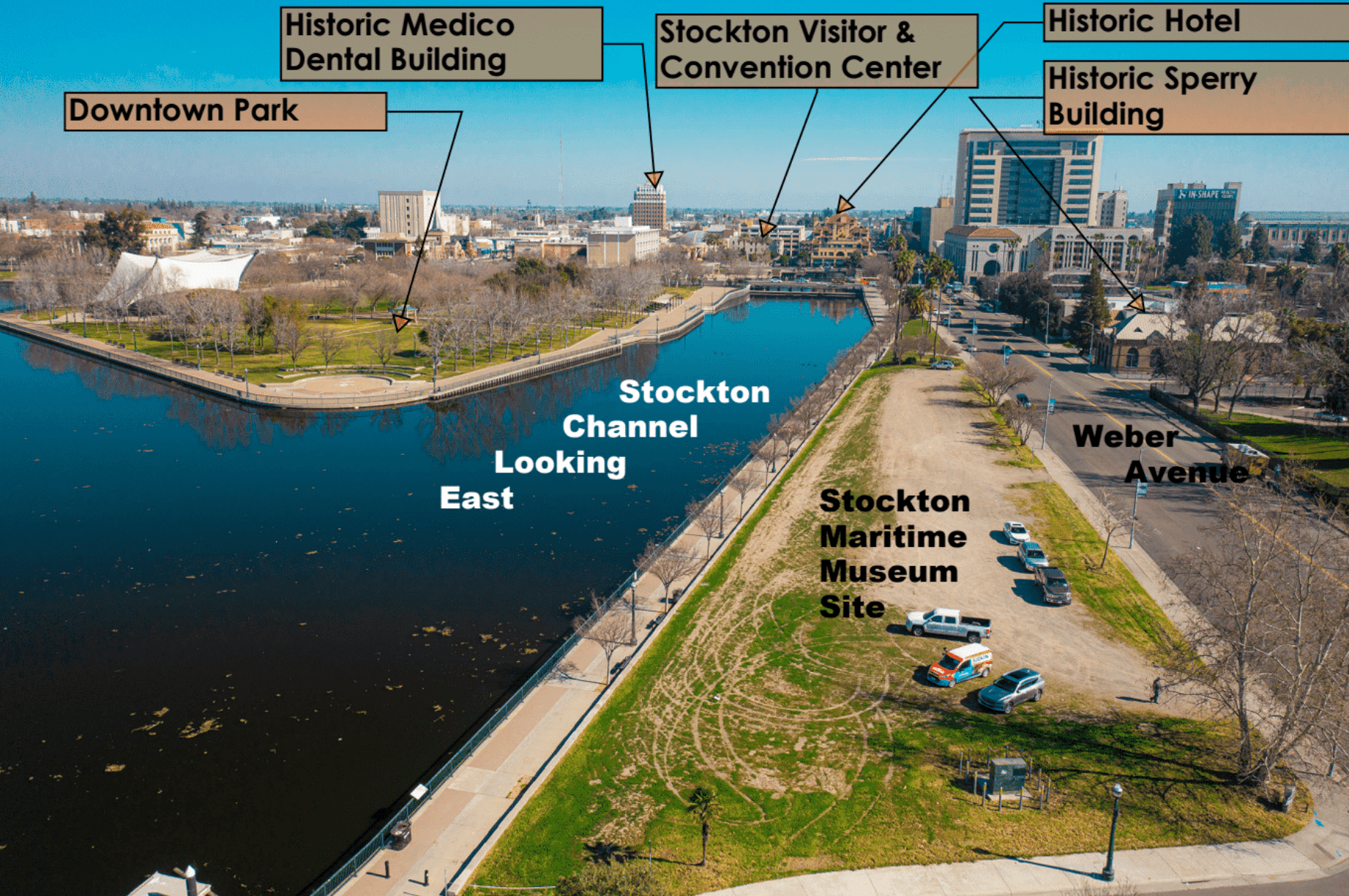 Aerial view looking east along the Stockton Channel showing the future Stockton Maritime Museum site on Weber Avenue, with nearby downtown landmarks including the park, Visitor and Convention Center, historic hotel, and Sperry Building.